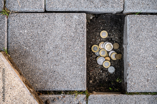 Polish zloty coins found under a loose pavement brick. Concept of running out of personal savings