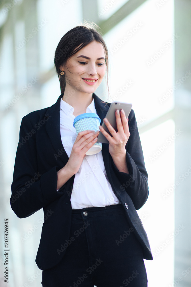 Business woman with coffe and talking on the phone near office Business woman with coffe and talking on the phone near office