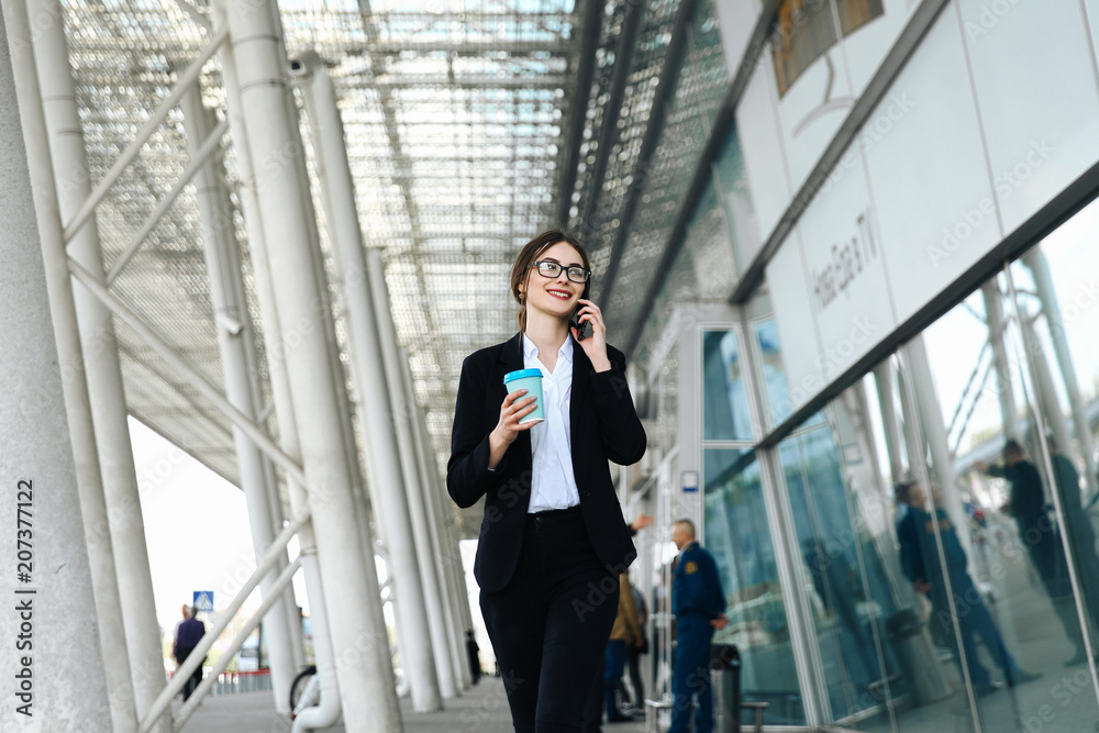 Business woman with coffe and talking on the phone near office Business woman with coffe and talking on the phone near office