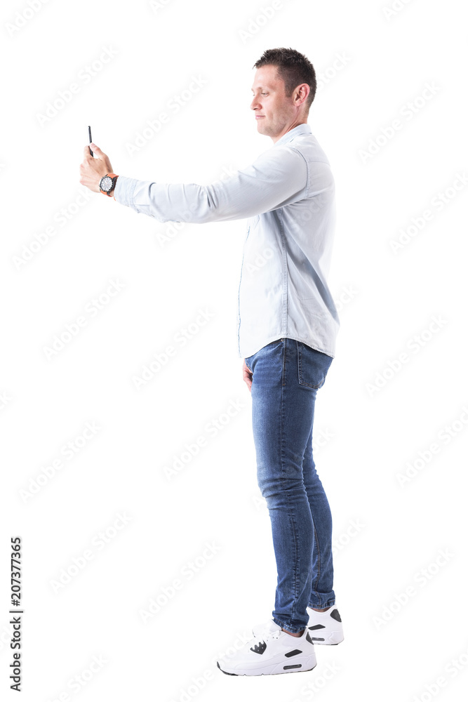 Relaxed young caucasian adult man taking self portrait with smart phone. Full body isolated on white background. Relaxed young caucasian adult man taking self portrait with smart phone. Full body isolated on white background.