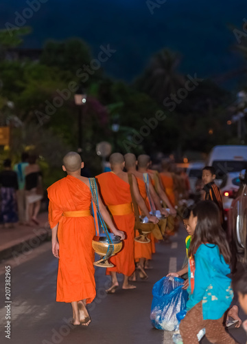 LUANG PRABANG, LAOS - JANUARY 11, 2017: Feeding the monks. The ritual is called Tak Bat. Vertical. Copy space for text.