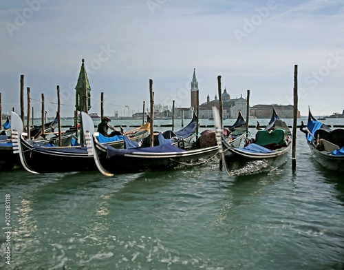 Many gondolas parked in the Venetian lagoon photographed with th