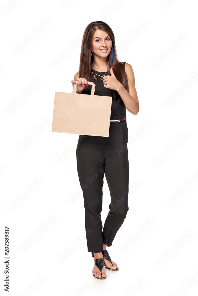 Full length woman holding carton brown shopping bag with empty copy space and gesturing thumb up Full length woman holding carton brown shopping bag with empty copy space and gesturing thumb up