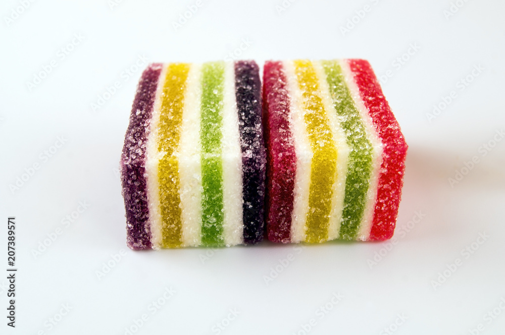 Multicolored marmalade sprinkled with sugar in a strip on a light background Multicolored marmalade sprinkled with sugar in a strip on a light background