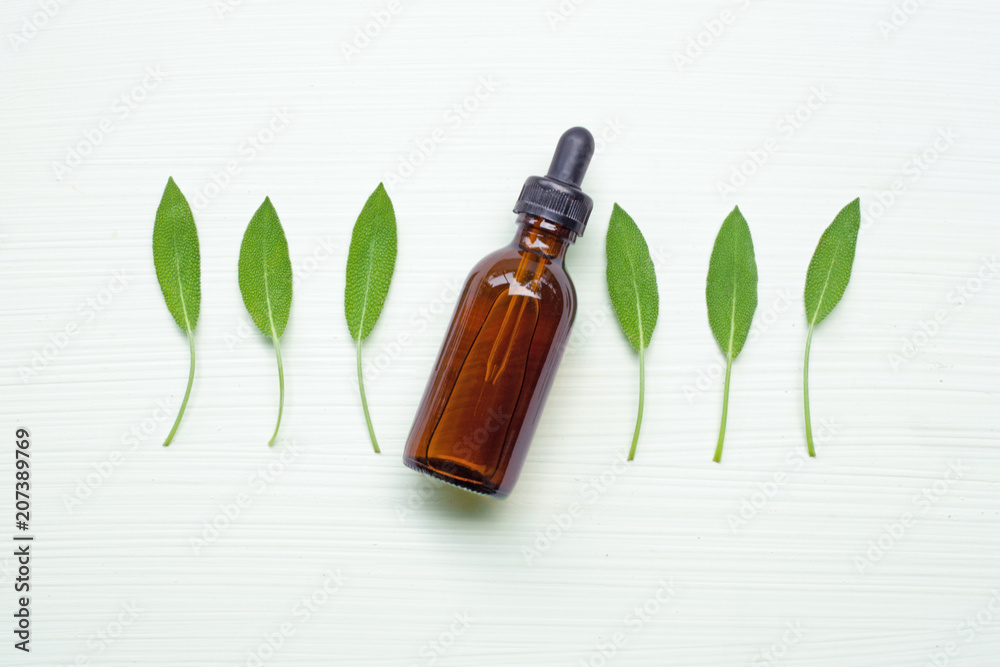 Sage essential oil with sage leaves on white blackground. Sage essential oil with sage leaves on white blackground.