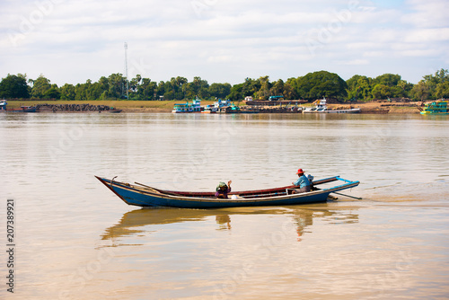 Fototapeta Naklejka Na Ścianę i Meble -  MANDALAY, MYANMAR - DECEMBER 1, 2016: A man and a woman in a boat on the Irravarddy river, Burma. Copy space for text.