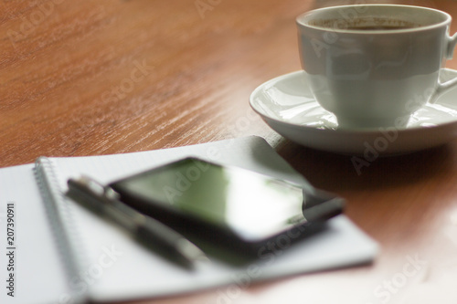 morning hot coffee, notebook and phone on the table
