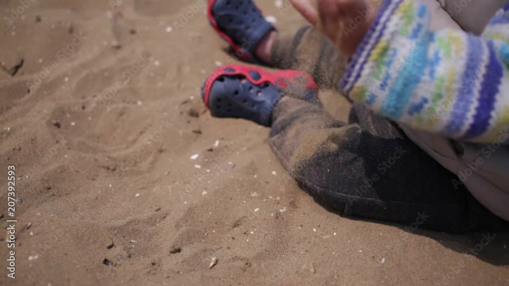 Children's hands are playing with sand on the beach.
Children's hands are playing with sand on the beach.