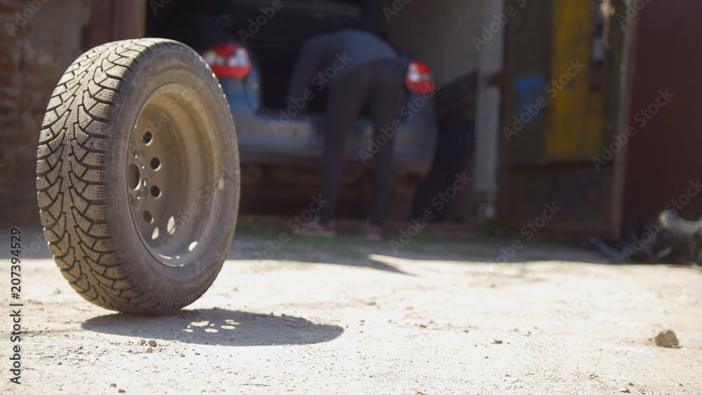 Car wheels rolling on the ground in front of car garage Car wheels rolling on the ground in front of car garage