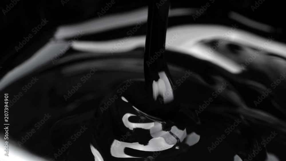 Black viscous liquid flows. Close up.
