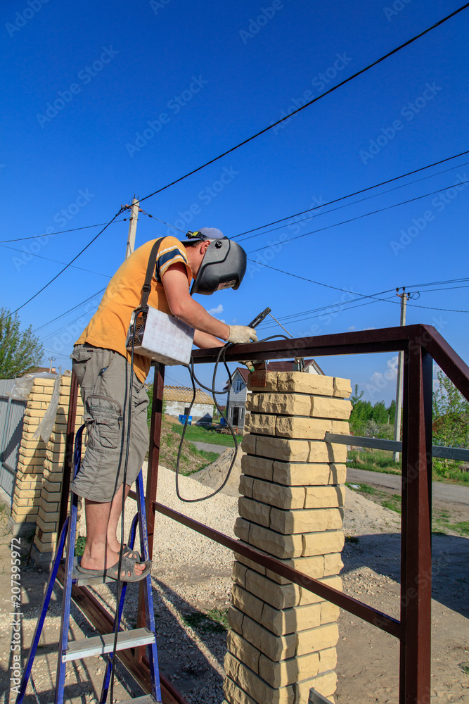 The worker installs rollers on the sliding gate The worker installs rollers on the sliding gate