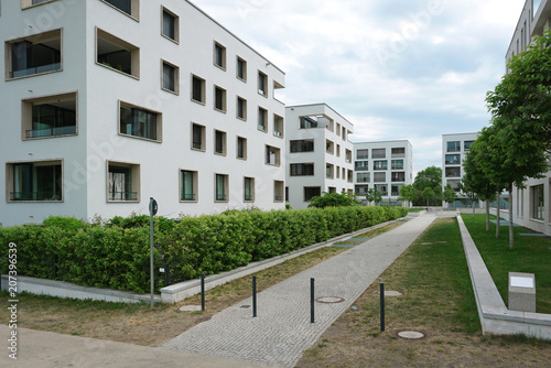 Row of white residential buildings with balconies and rectangular windows in a modern district.