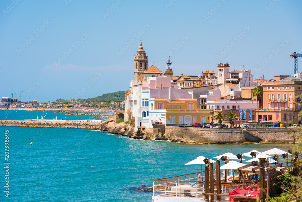 SITGES, CATALUNYA, SPAIN - JUNE 20, 2017: View of the historical center and the church of Sant Bartomeu and Santa Tecla. Copy space for text. Isolated on blue background.