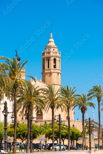 SITGES, CATALUNYA, SPAIN - JUNE 20, 2017: View of the embankment and ñhurch of Sant Bartomeu and Santa Tecla. Copy space for text. Isolated on blue background. Vertical.