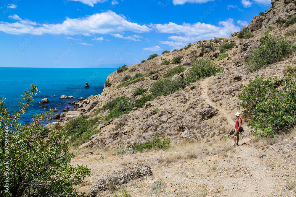The tourist admires the Sea and Mountains landscape at Cape Meganom, the east coast of the peninsula of Crimea.