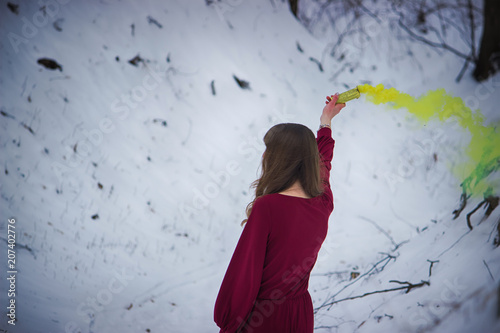 Young girl holds in her hand colorful smoke of many colors photo