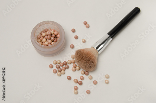 Women's cosmetics, highlighter pearls and makeup brush on white background. Decorative cosmetics