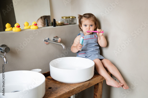 Toddler brushing teeth on bathroom counter photo