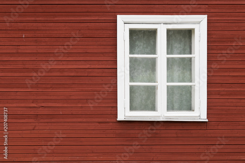 White window covered with lace curtains on red wooden wall, in Estonia. © uduhunt
