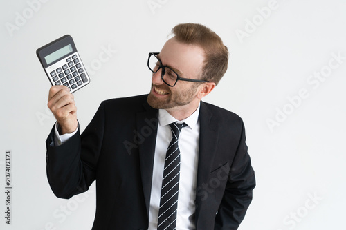 Smiling business man holding, showing calculator display and looking at it. Calculation concept. Isolated front view on white background.