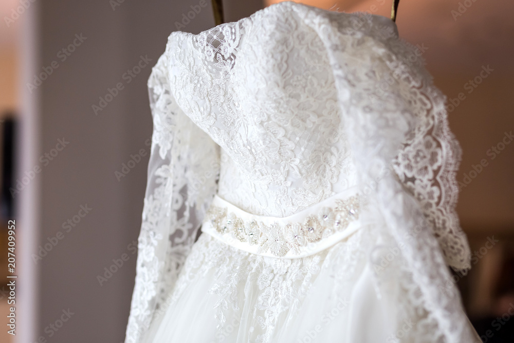 beautiful wedding dress hanging in the room, woman getting ready before ceremony beautiful wedding dress hanging in the room, woman getting ready before ceremony