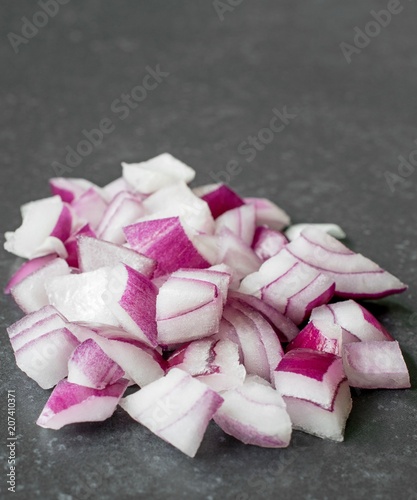 A small pile of chopped up red onions on a dark stone surface