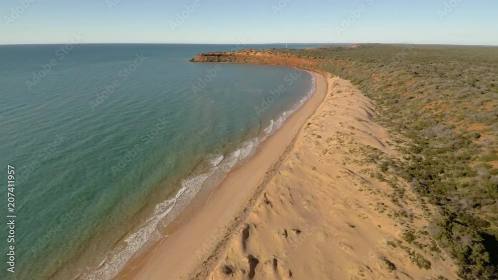 A medium shot of a shoreline and the sea with grassy land. Camera slowly moves forward A medium shot of a shoreline and the sea with grassy land. Camera slowly moves forward
