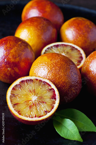 Whole and sliced blood oranges, close-up photo