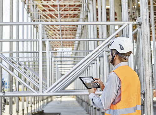 Architect with tablet wearing hard hat on construction site photo