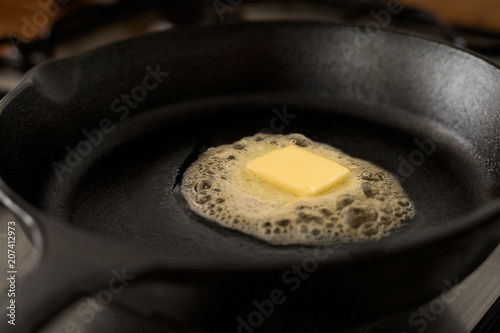 Quadro su tela A butter pat melting on a black cast iron frying pan.