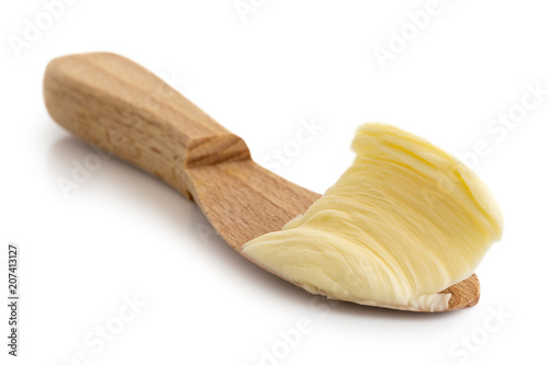 Butter spread on wooden knife isolated on white. photo