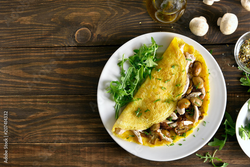  Omelette stuffed with mushrooms, pieces of chicken meat, greens photo