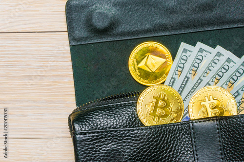 Crypto currency. Coins Bitcoin (BTC), banknotes one hundred dollars sticking out of a man's black leather purse on a wooden background.Blockchain.Intarnational currency.Top view.E-commerce.E-business. photo