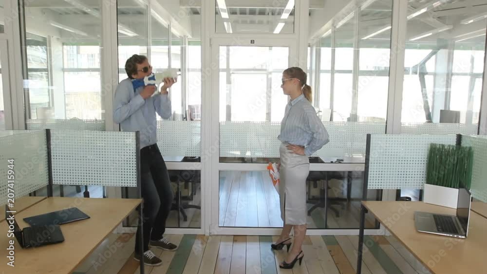 Workers in sunglasses playing with water pistols in office Workers in sunglasses playing with water pistols in office