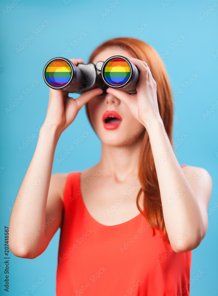 Redhead girl with binocular and gey flag on blue background. Redhead girl with binocular and gey flag on blue background.