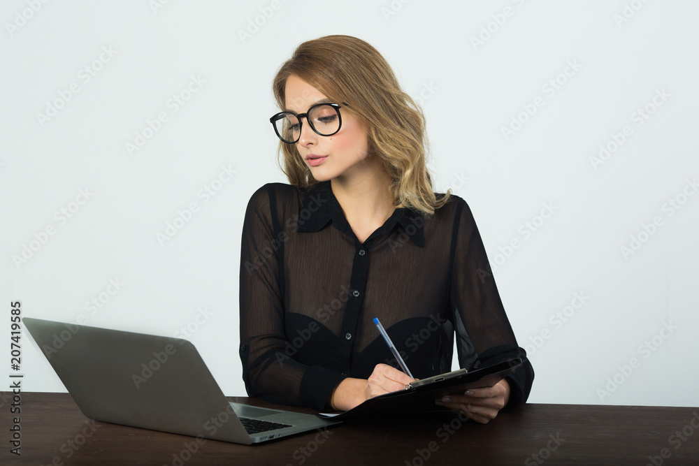 beautiful young girl with glasses sitting at the table with a laptop on a white background beautiful young girl with glasses sitting at the table with a laptop on a white background