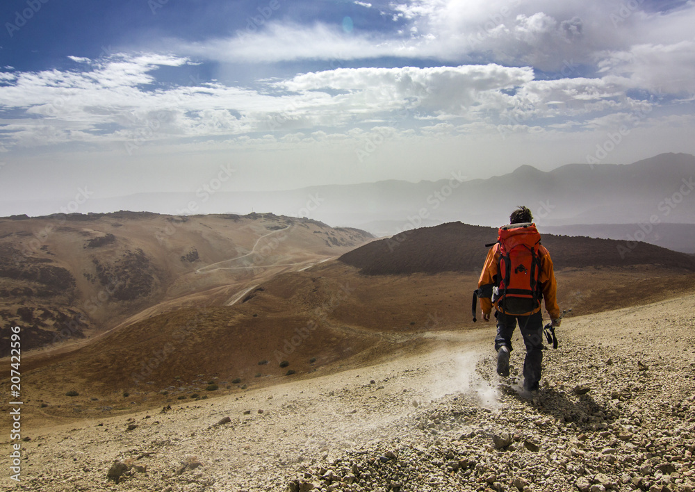 man with red backpack on rocky path in desert