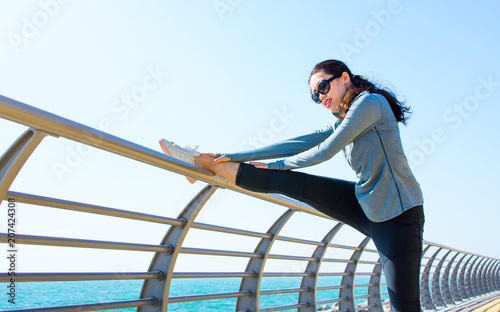 Girl warming up for a workout by the seaside
