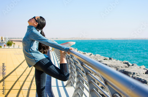 Fototapeta Naklejka Na Ścianę i Meble -  Girl stretching before workout by the seaside