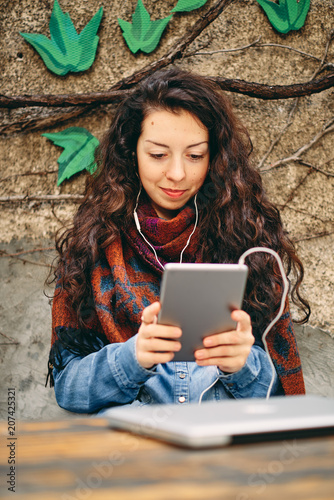 Head shot of woman listening to the music on tablet while sitting in the garden.