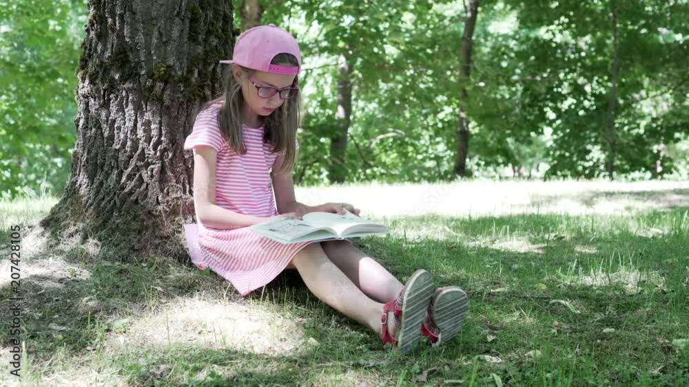 Girl reading a book sitting under a tree shadow 4K Girl reading a book sitting under a tree shadow 4K