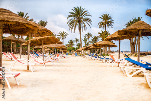 Sunbeds with parasols on snow-white sand on beach