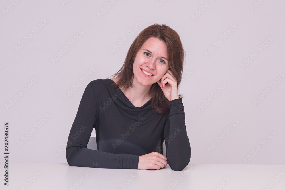 Portrait of beautiful brunette girl on white background sitting at table. Portrait of beautiful brunette girl on white background sitting at table.