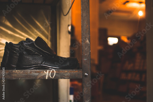 Emergency services work boots. Heavy black leather shoes used in cases of natural disasters, ecological catastrophes, armed conflicts, fires. Boots laying on the wooden shelf in the storage.
