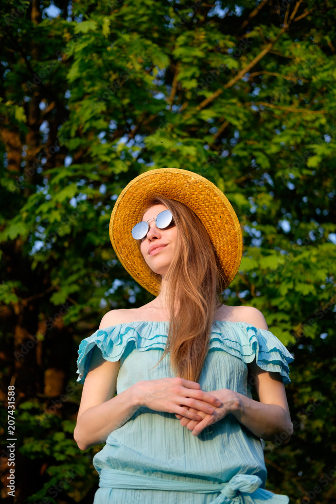 Redhead skinny girl in blue dress, mirror sunglasses and straw hat portrait in sunset light