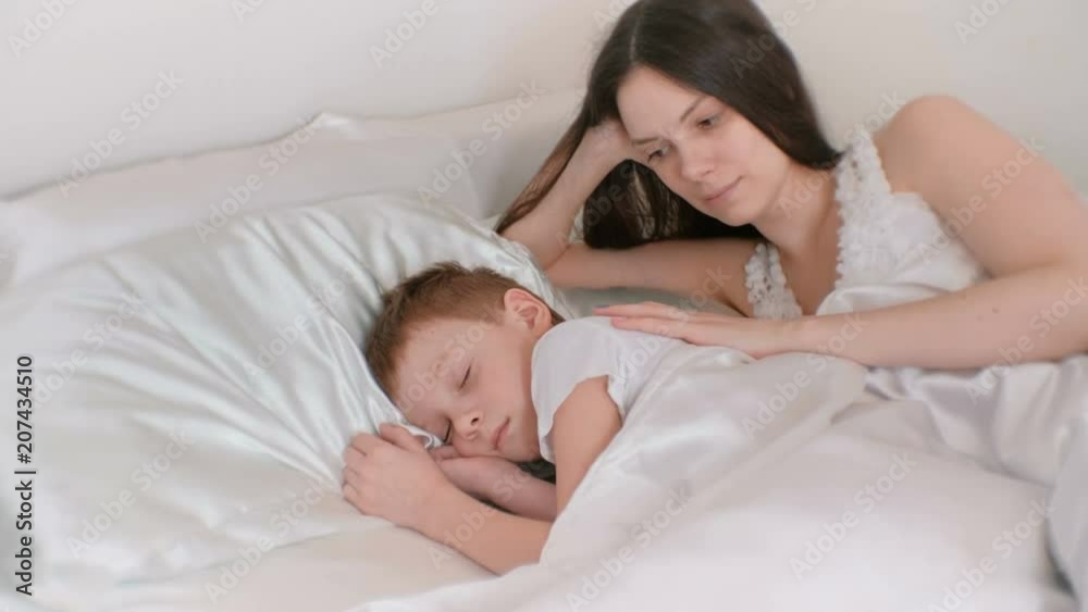 Mom puts her son to bed. Stroking his back and kissing. Mom puts her son to bed. Stroking his back and kissing.