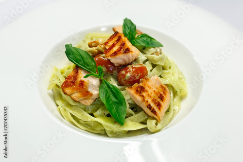 Italian pasta fettuccine with salmon and tomatoes on a white plate