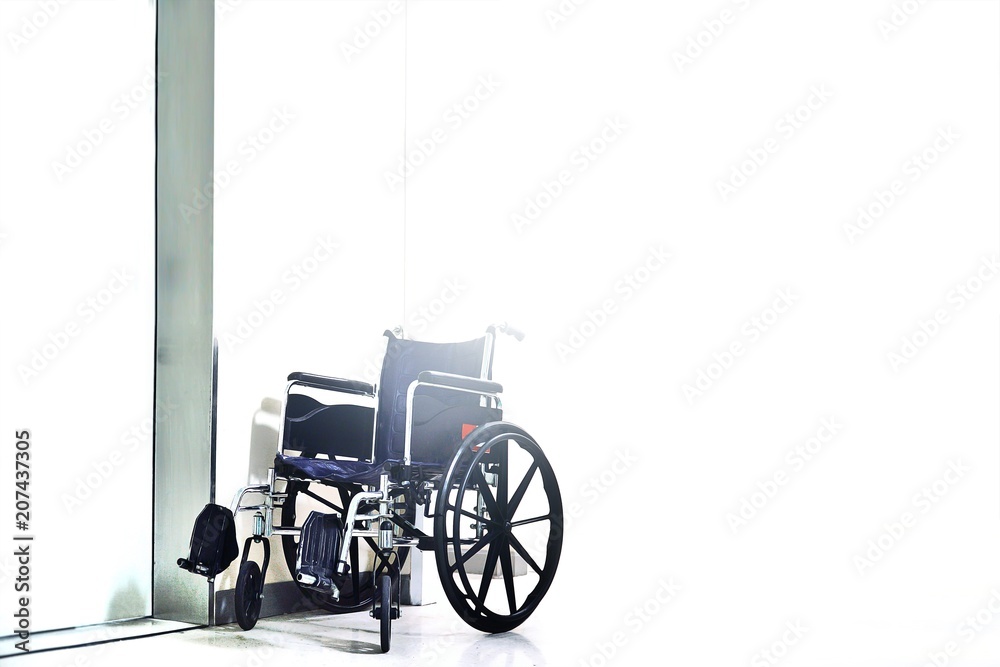 Black and silver invalid wheel chair in hospital on white background with light.Health care and Disability people concept.Copy space empty blank for text.