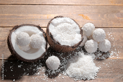 Halves of coconut with coconut chips and coconut sweets on a brown wooden background