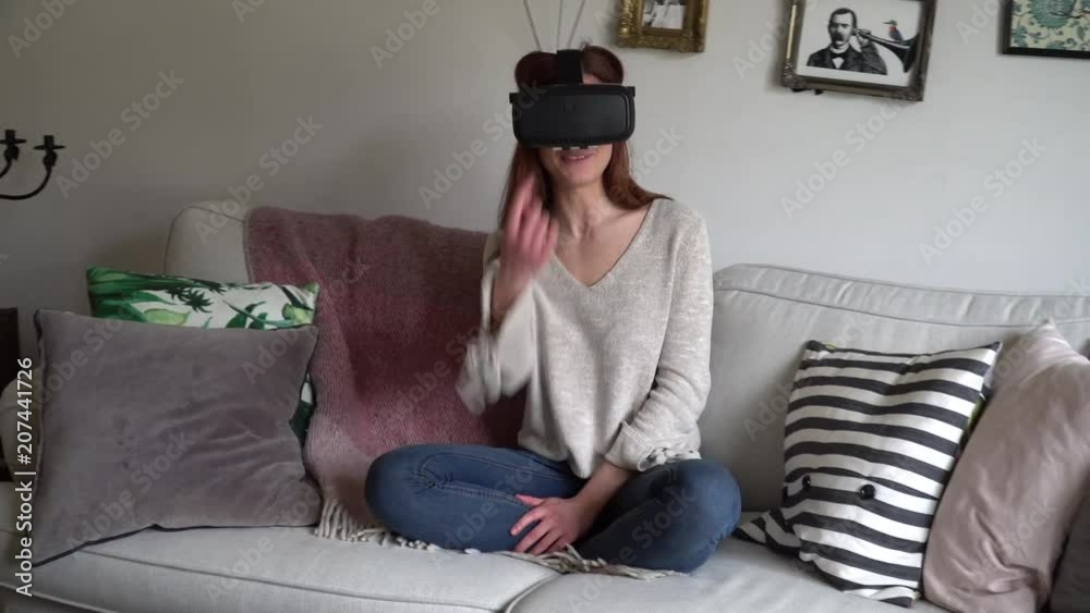Young Swedish girl sits in a couch, using a VR headset Young Swedish girl sits in a couch, using a VR headset